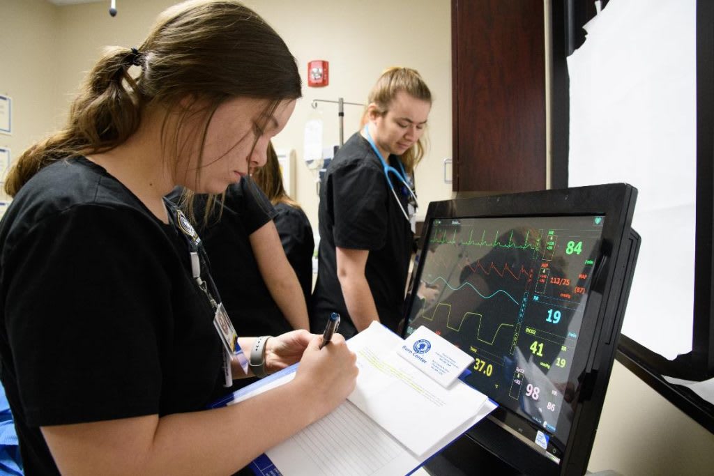 Nursing student taking notes from monitor