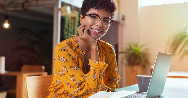 smiling woman sitting at table with a laptop