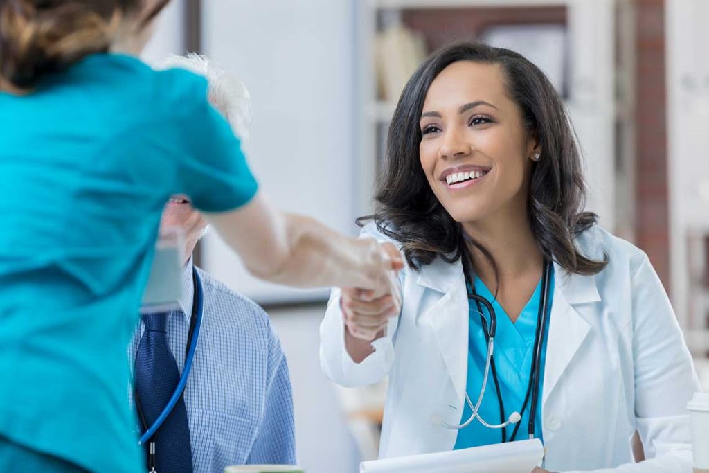 two nurses at table shaking hands