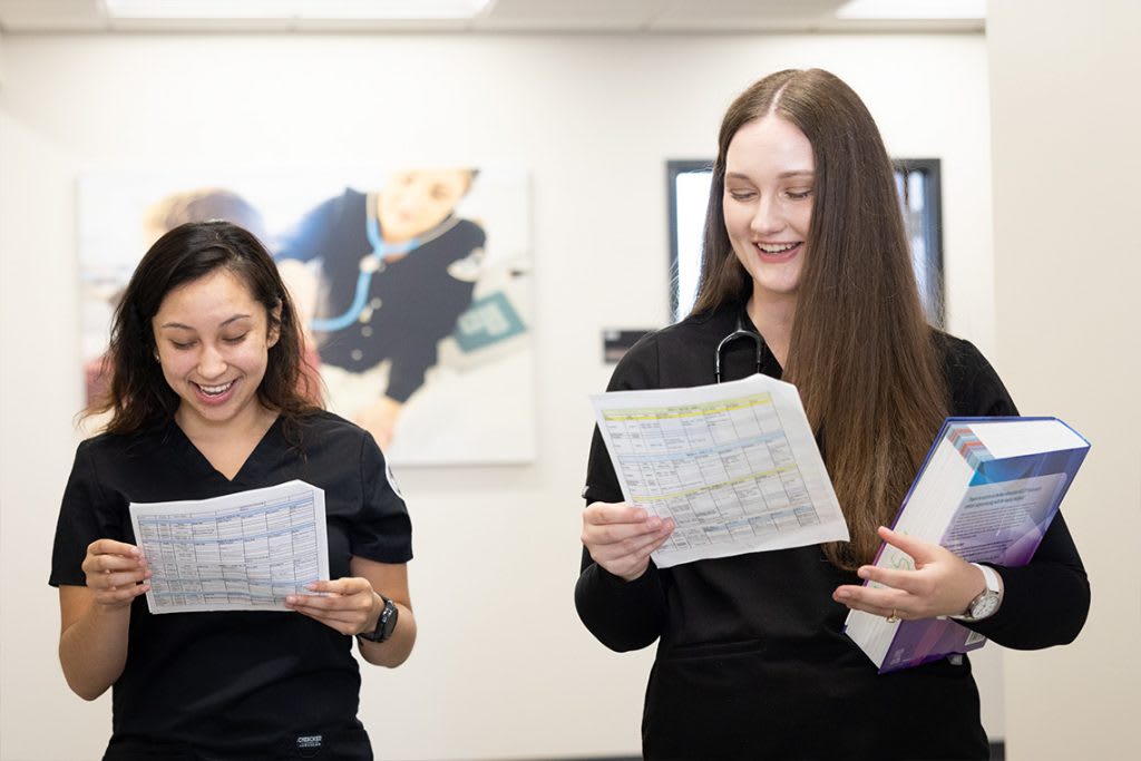 nursing students holding books walking down the hall