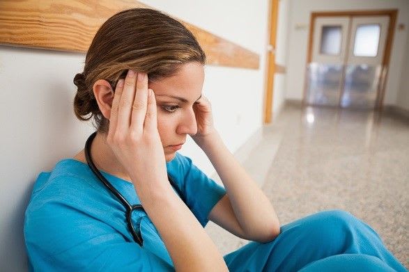 nurse sitting on floor with hands on head