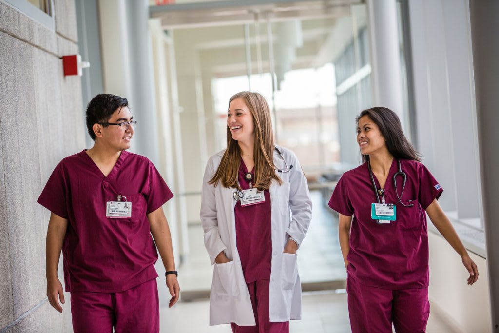 3 nursing students walking in red scrubs
