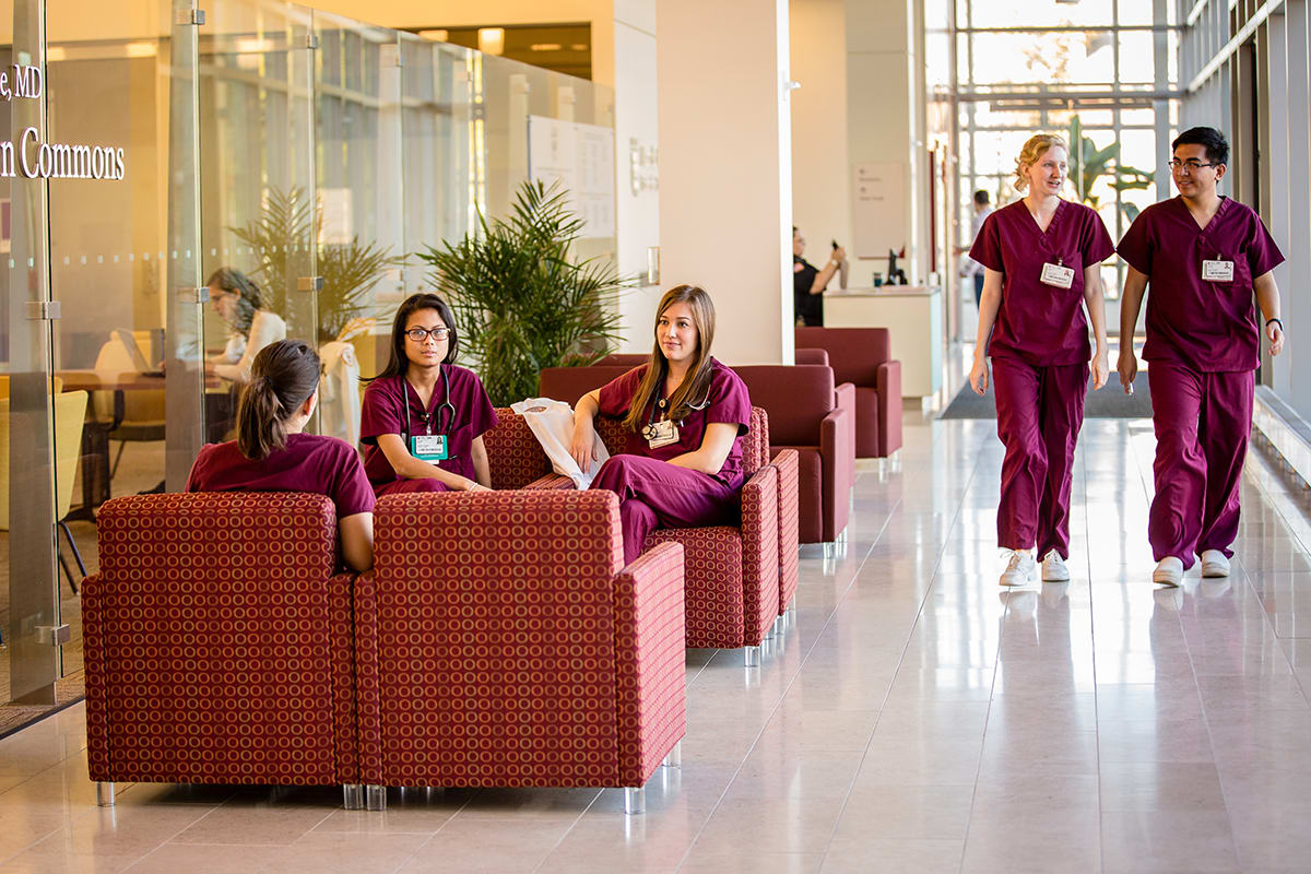 nursing students gathered in hallway in red scrubs