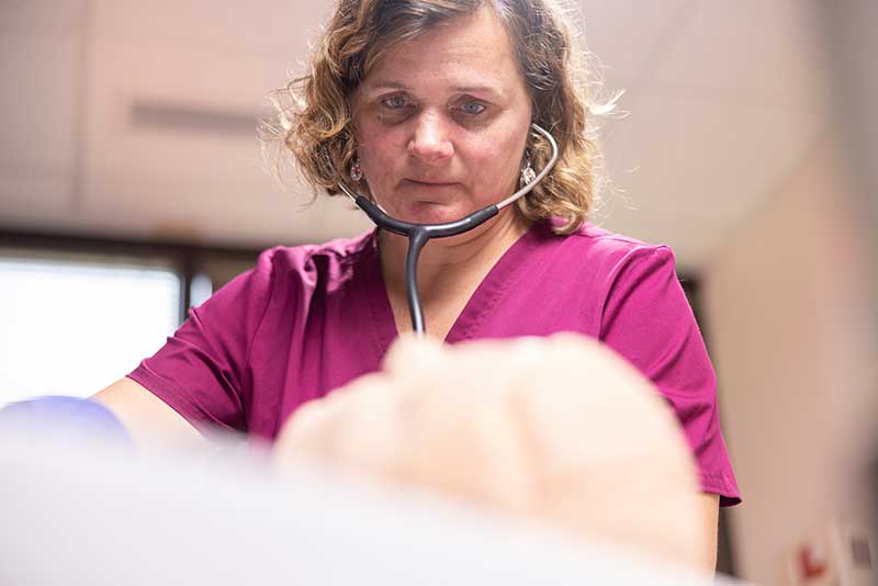 nursing student using stethoscope in simulation lab