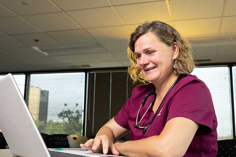 nursing student sitting at desk using a laptop