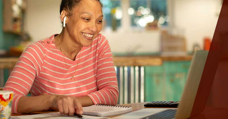 woman wearing airpod headphones sitting at desk using a laptop