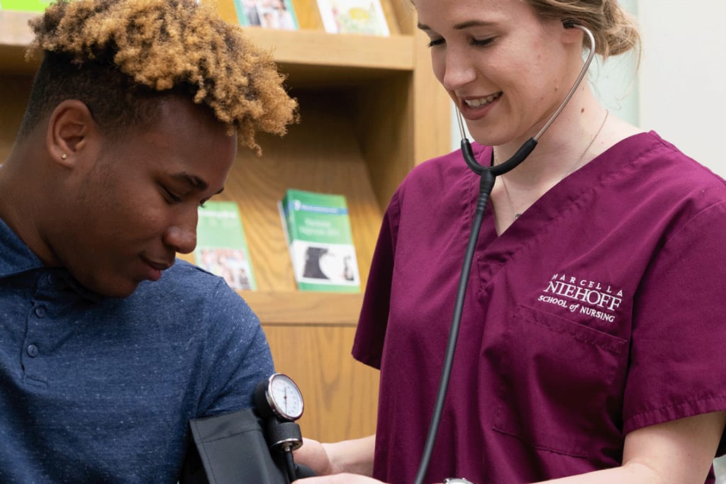 Loyola nursing student using stethoscope on another student