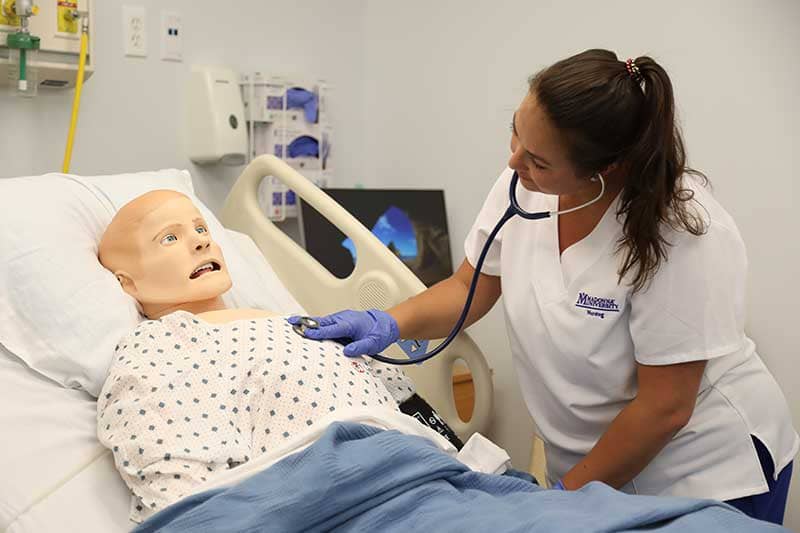 nursing student working with sim manikin