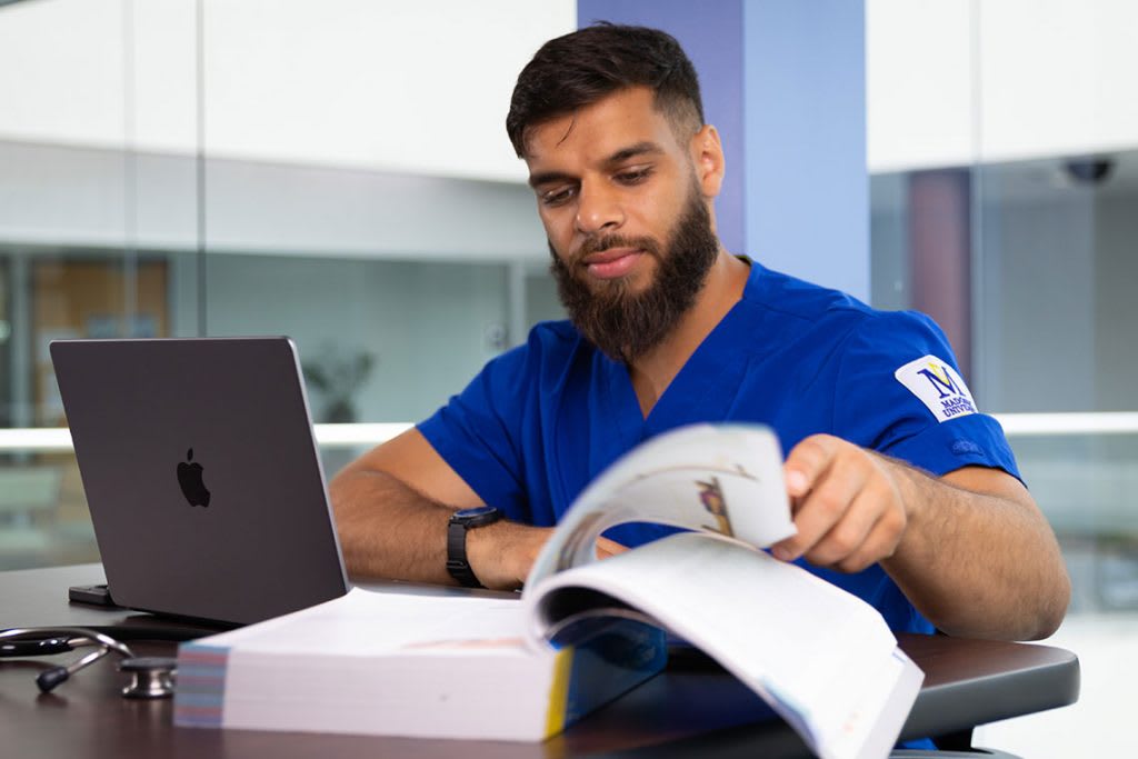 Madonna nursing student sitting and reading a textbook