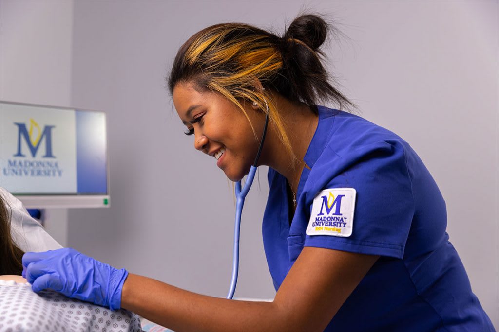 Madonna nursing student working with stethoscope on sim manikin