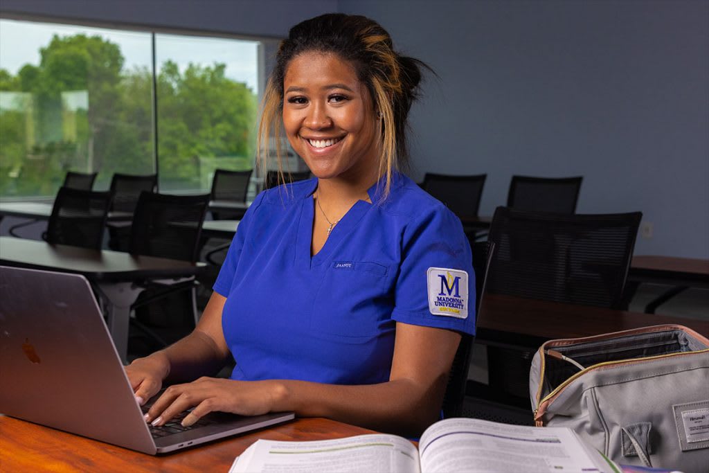 Madonna nursing student sitting at desk typing on laptop