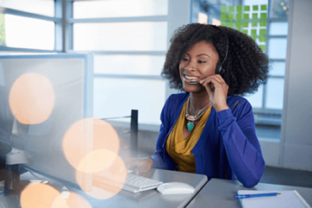 woman sitting at desk with computer and headset