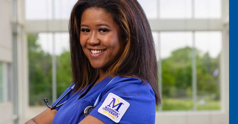 Madonna ABSN student in blue scrubs posing and smiling