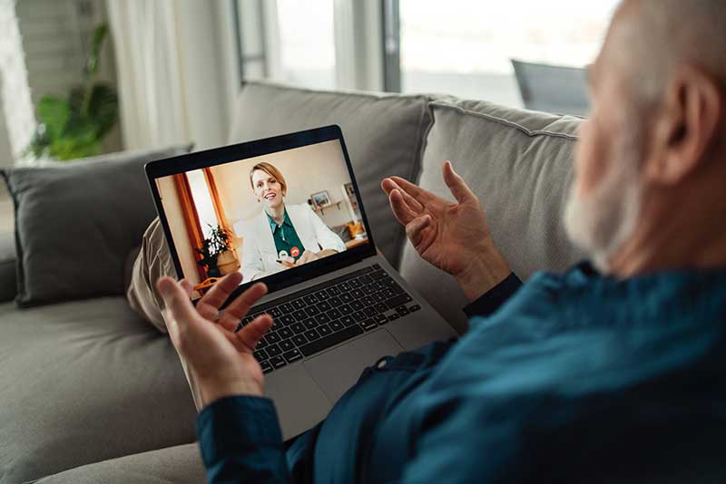 elderly patient at home talking with a doctor virtually on a computer