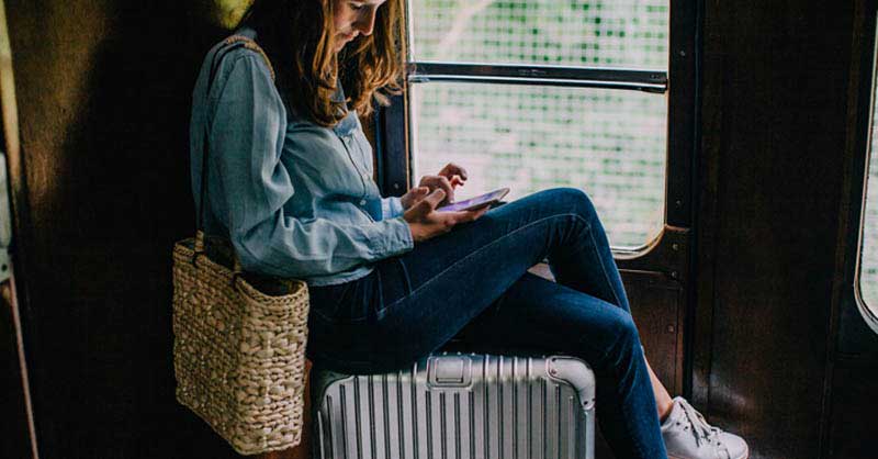 Girl sitting on suitcase while riding train