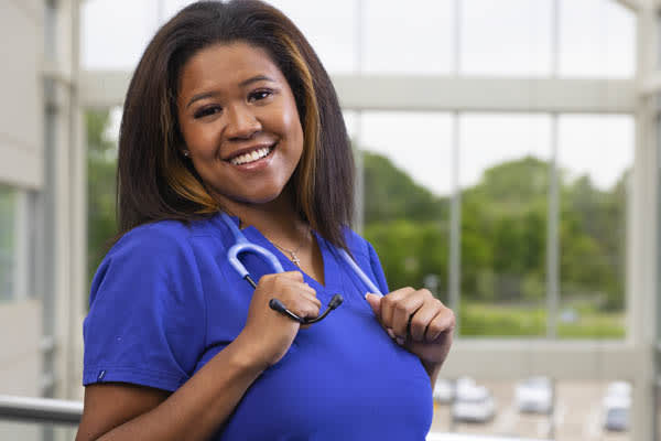 student posing smiling at camera in scrubs