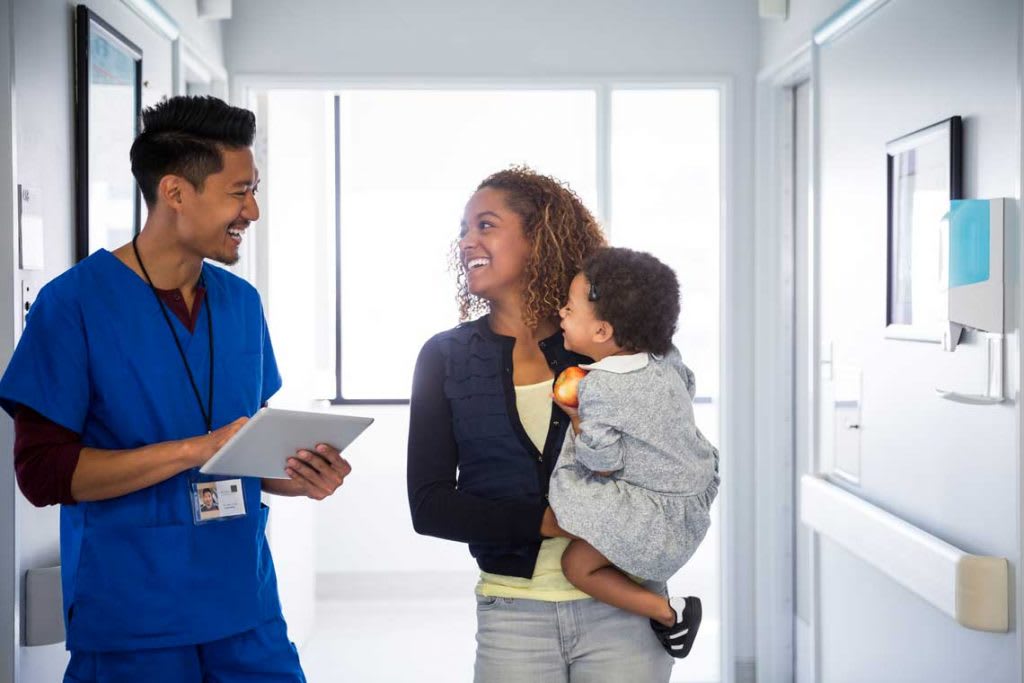 Nurse in hallway smiling and talking with patient