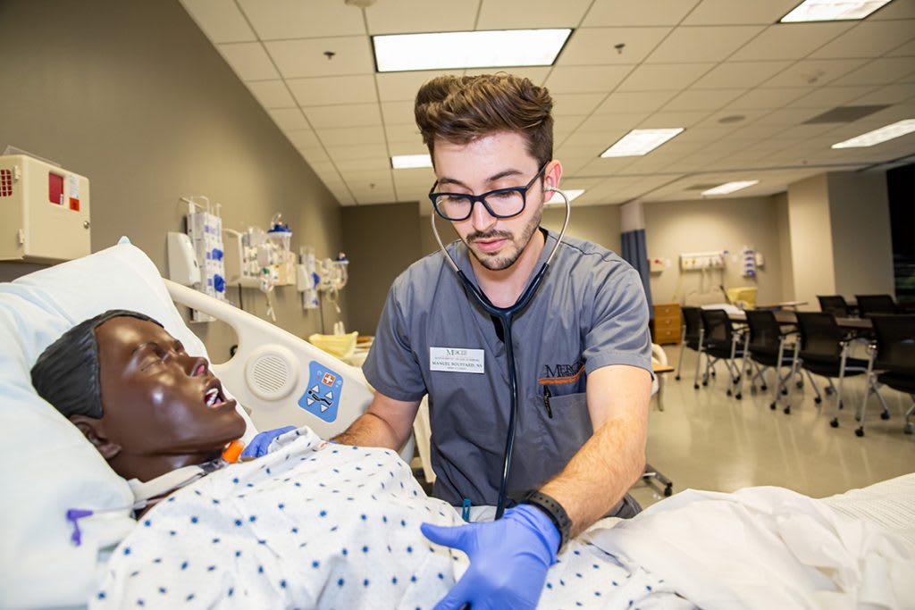 nursing student using stethoscope on simulation manikin