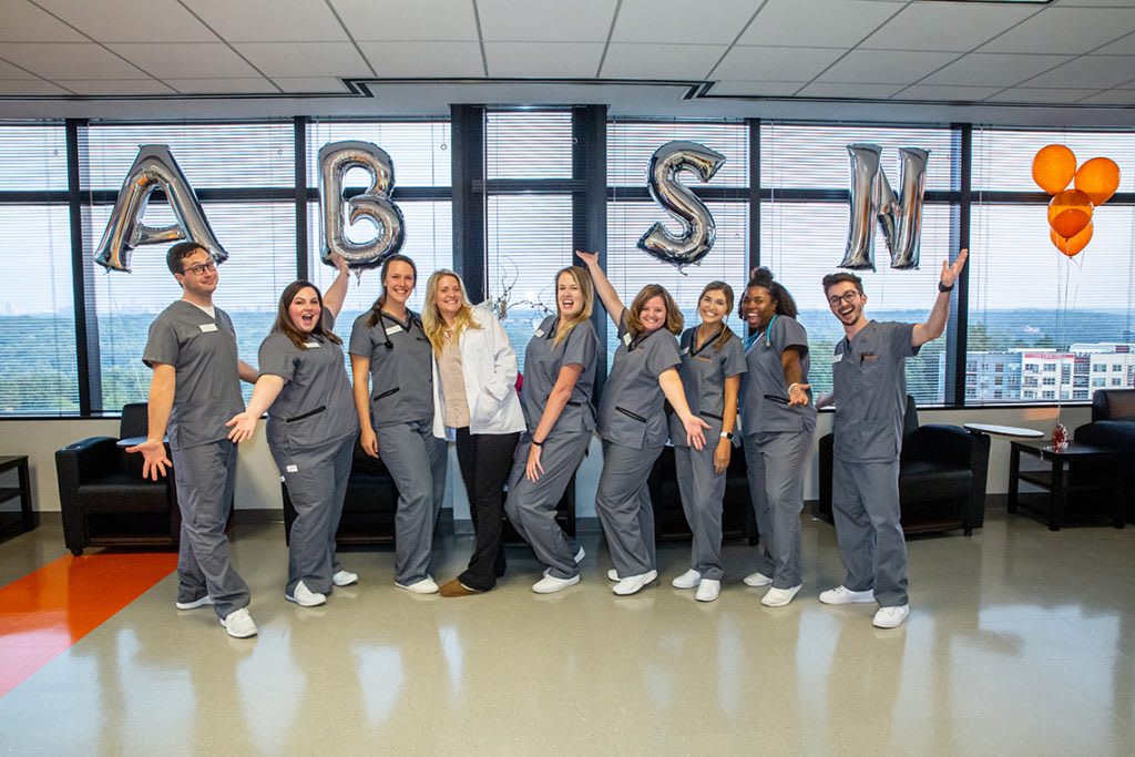 nursing students holding balloons spelling out ABSN