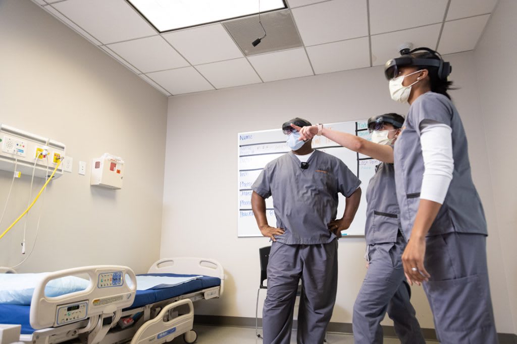 nursing students in lab pointing at wall