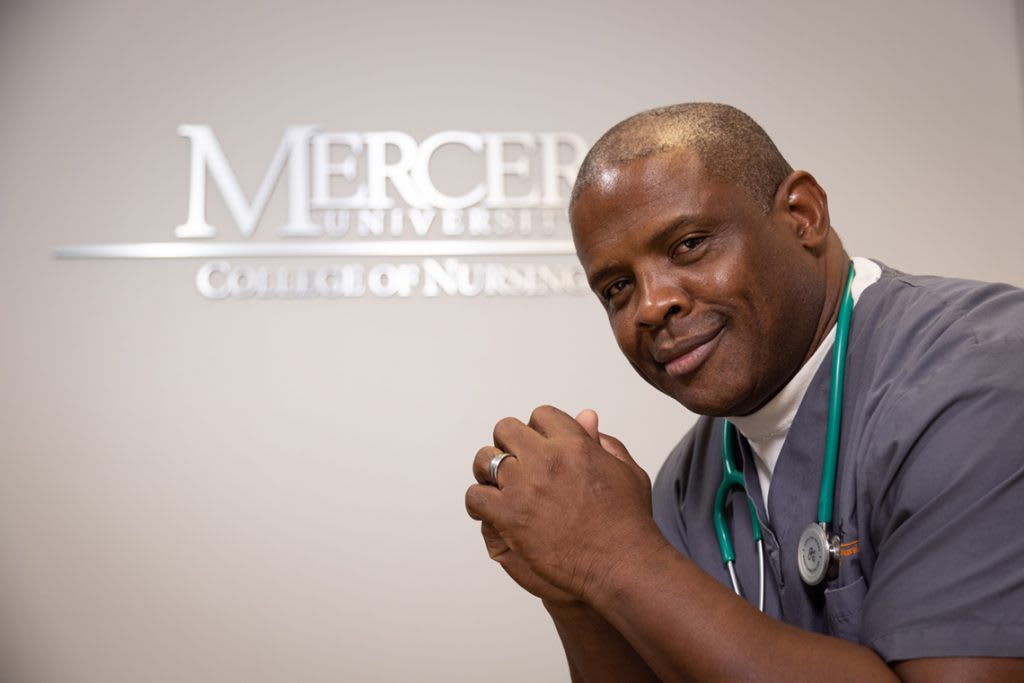 Mercer nursing students sitting in front of Mercer University wall sign