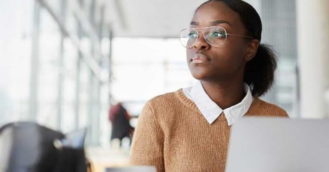 woman sitting at desk looking out window