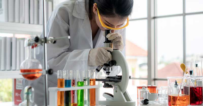 Scientist in lab coat using microscope