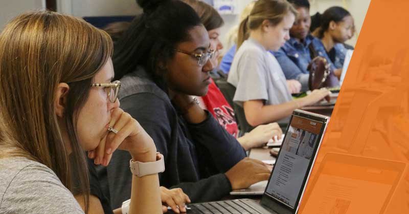 students sitting at table using laptops