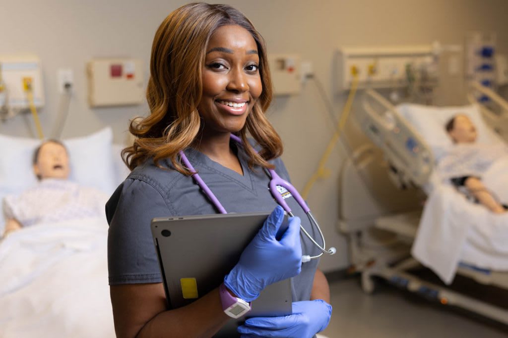 student smiling at camera in mock hospital room