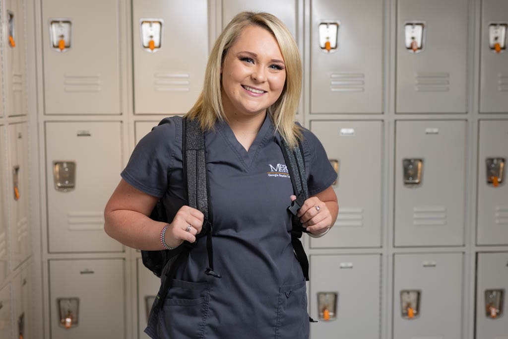 Mercer ABSN student with backpack standing by lockers