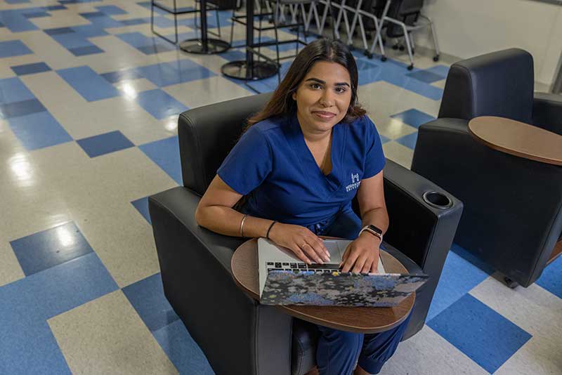 ABSN student sitting in chair using laptop