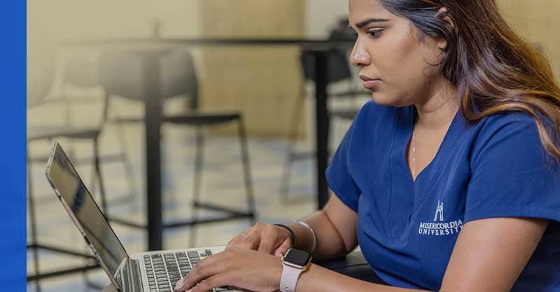 Misericordia ABSN student sitting with laptop