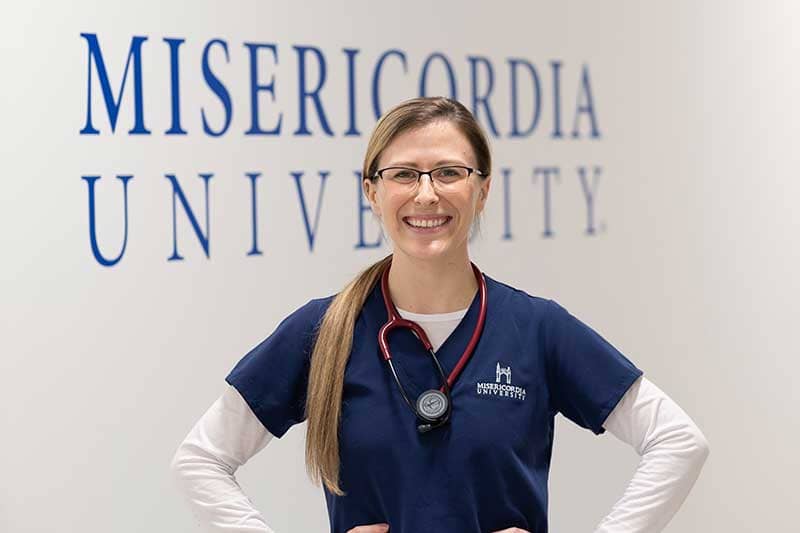 ABSN student standing in from of Misericordia University branded wall
