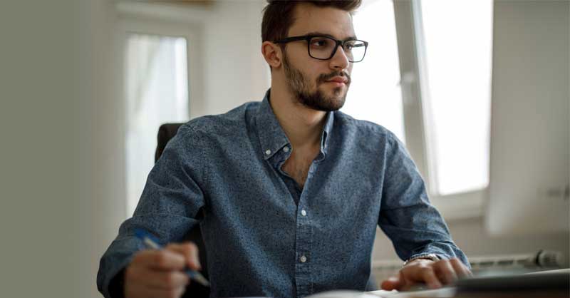 man sitting at a desk looking at his computer