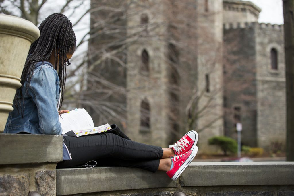 Student sitting outside reading a textbook