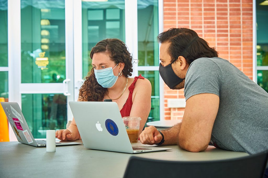 Students in masks working on computers outside