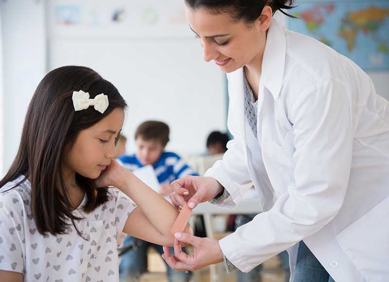 school nurse putting band-aid on child's arm
