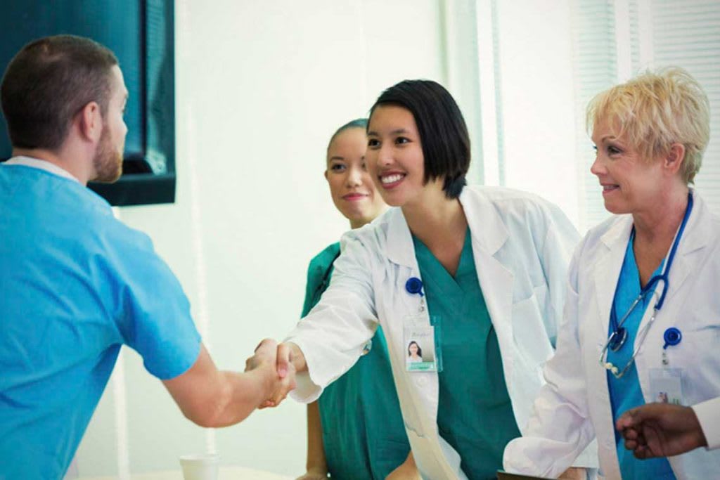 nurses shaking hands across a table