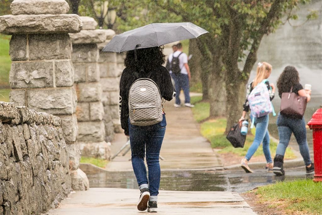 Student walking to class in the rain with an umbrella