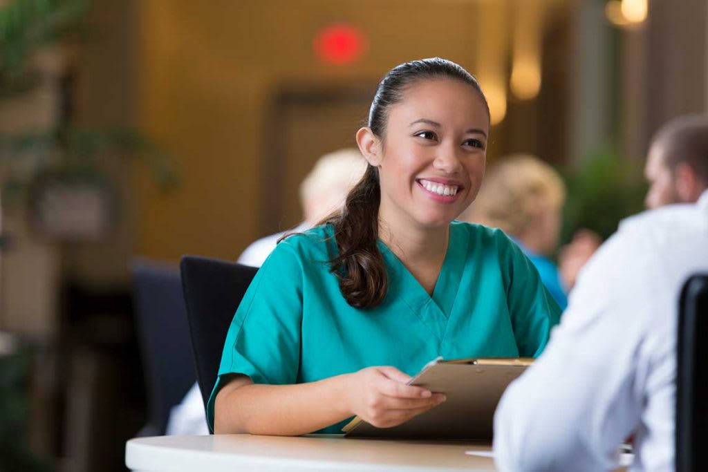 nurse sitting at table holding clipboard