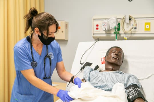 Nursing student in lab practicing on a manikin
