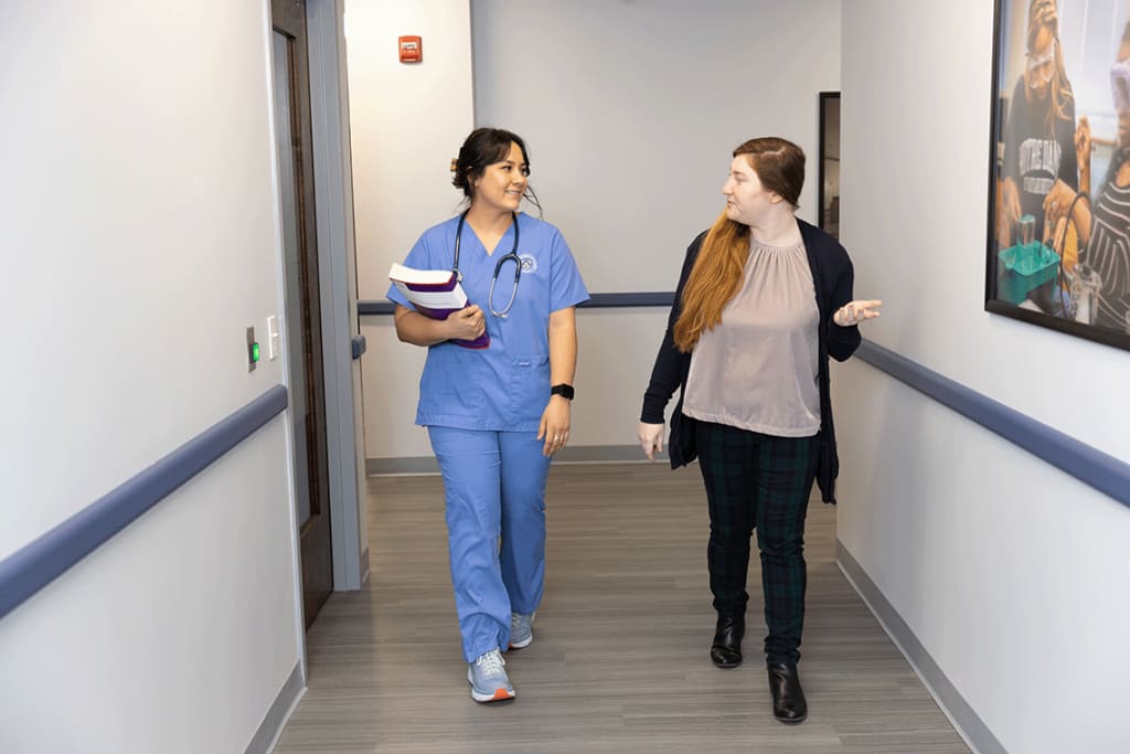 NDMU student walking the hallway with an instructor