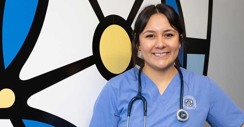 ABSN student in blue scrubs smiling