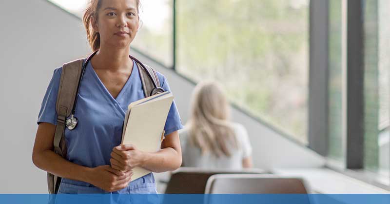 Nurse in blue scrubs holding clipboard