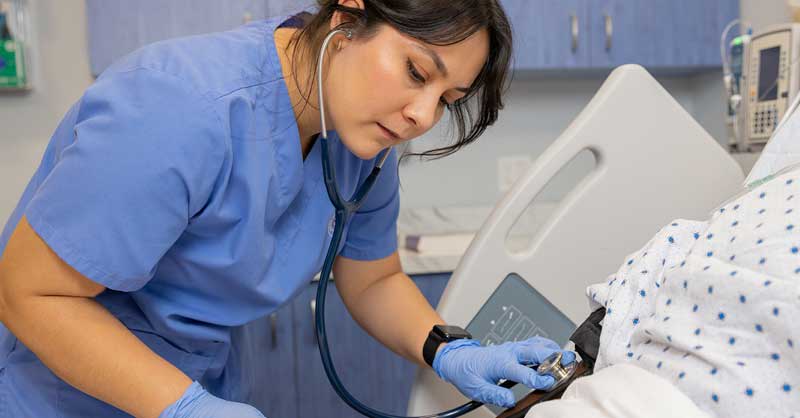 nursing student using stethoscope in sim lab