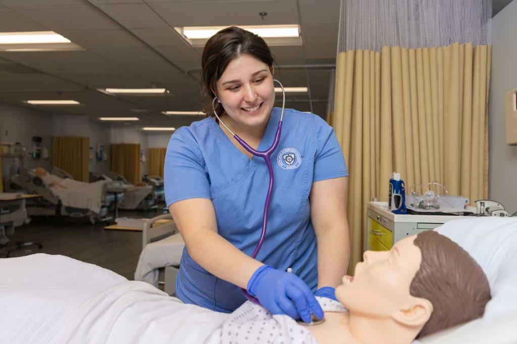 NDMU nursing student working with sim manikin