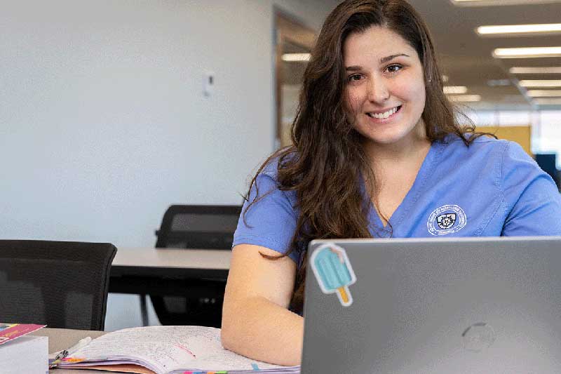 Nursing student sitting at desk working on computer