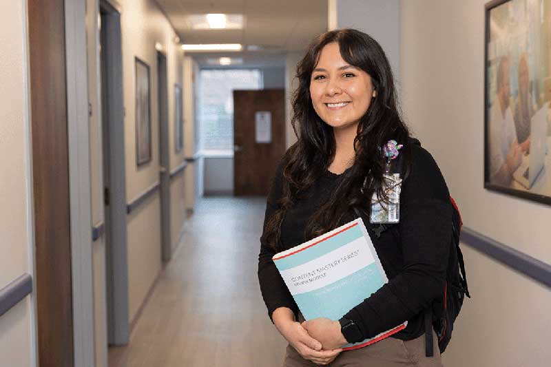 Nursing student standing in hallway holding textbooks