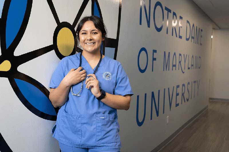 NDMU student smiling in blue scrubs and stethoscope