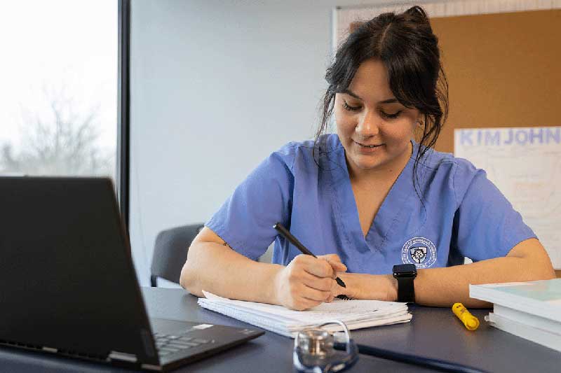 NDMU nursing student taking notes from computer